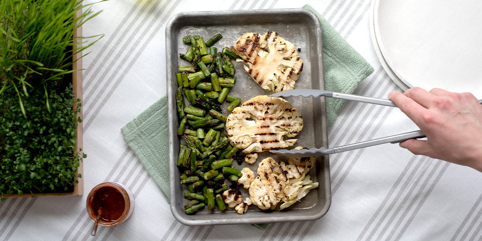 A half sheet pan filled with bite-sized just-grilled asparagus and slices of cauliflower