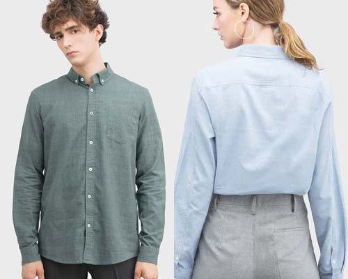 Man wearing olive green Cosmos Studio sustainable button down collar shirt and woman wearing light blue button down shirt tucked in to grey trousers