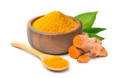 Turmeric powder in a wooden bowl beside a spoonful and turmeric root.