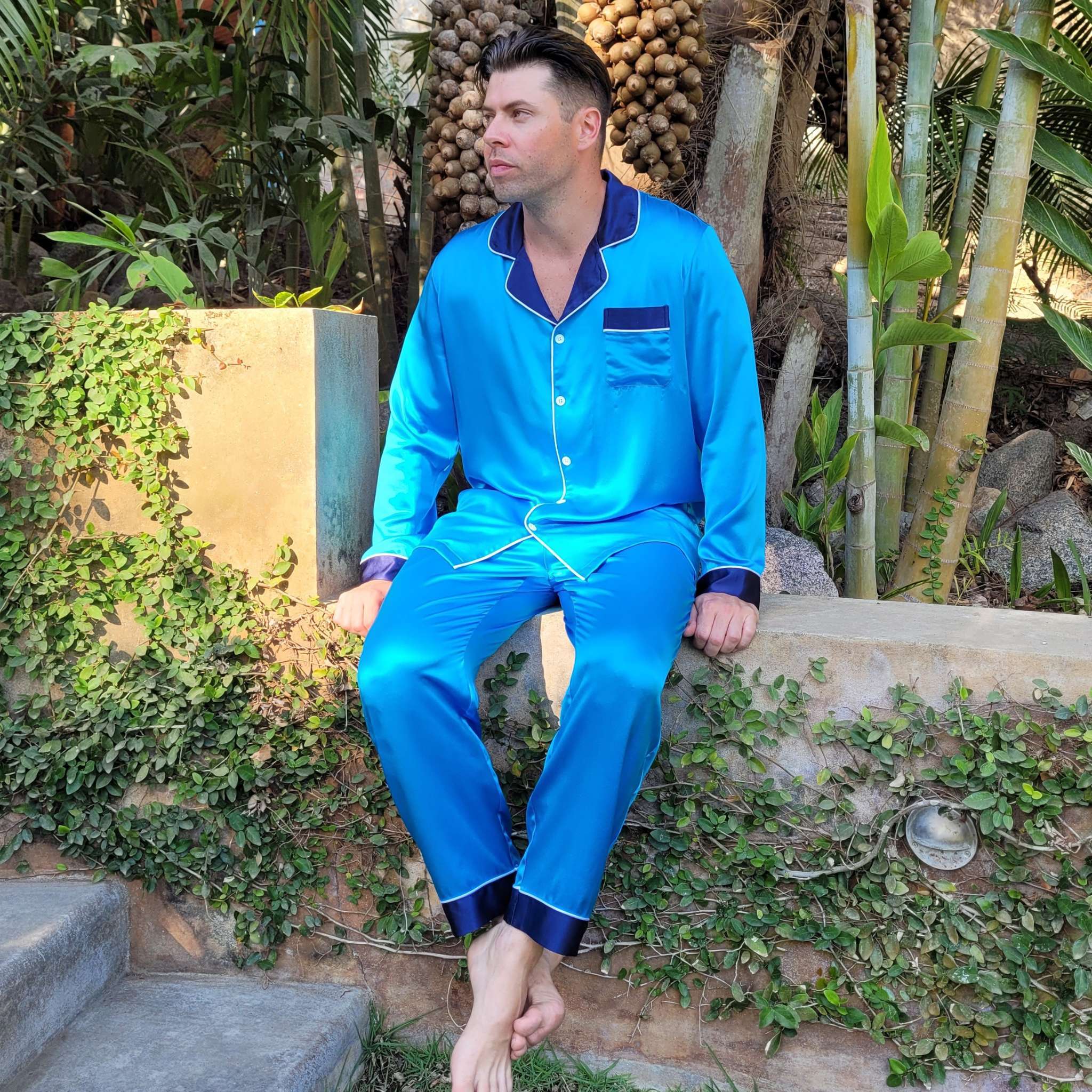 photo of a model sitting outside and wearing blue silk pajamas