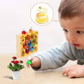 Baby boy playing with Montessori Bee Box and holding a green bee in his hand. 