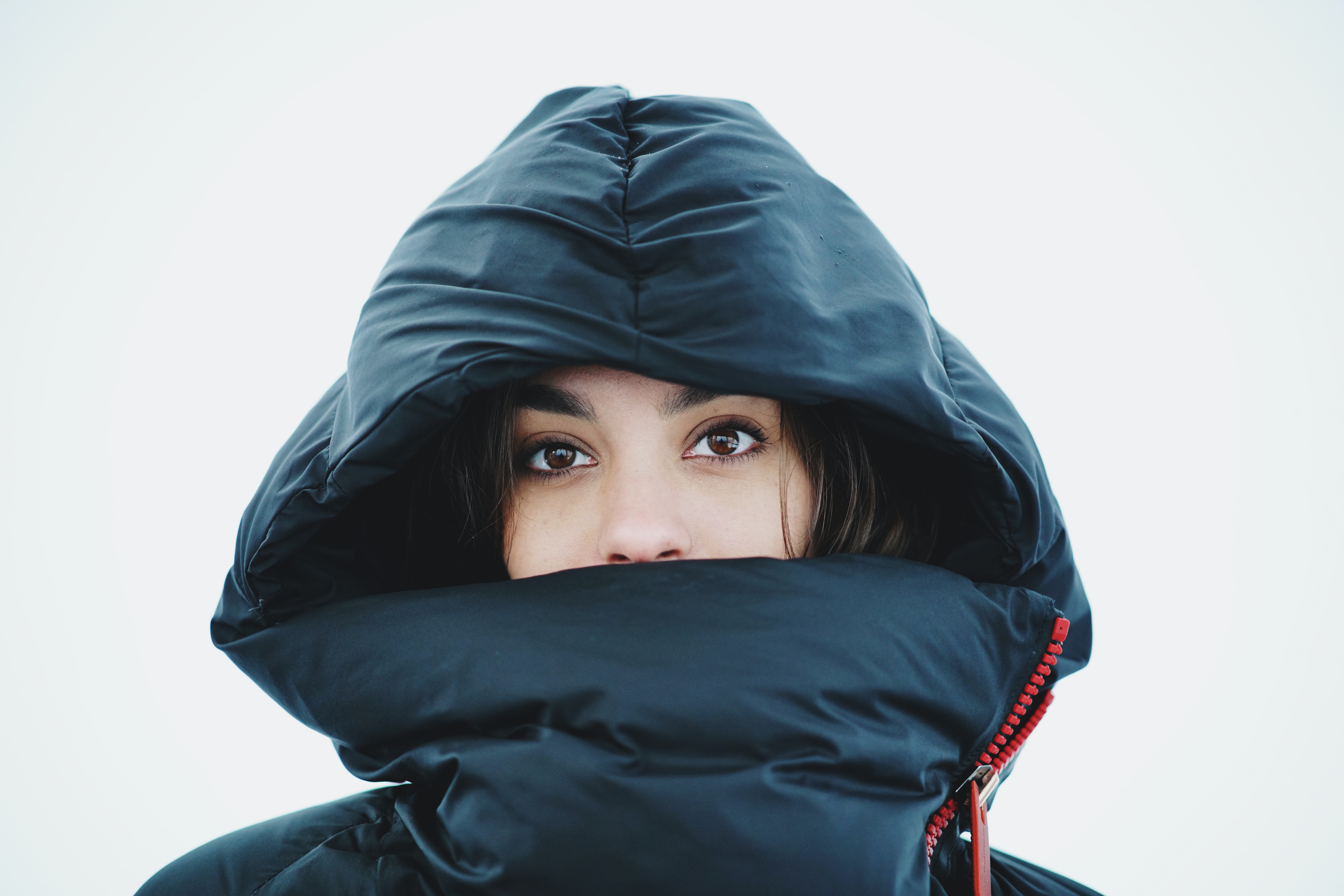 A woman wearing a big hoodie where you can only see her eyes and nose.