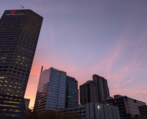 Cityscape at twilight with tall buildings, colorful sunset sky, evoking calmness, hope, and appreciation for urban beauty.