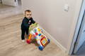 Baby using a push walking toy indoors while practicing balance and early walking skills on a safe open floor