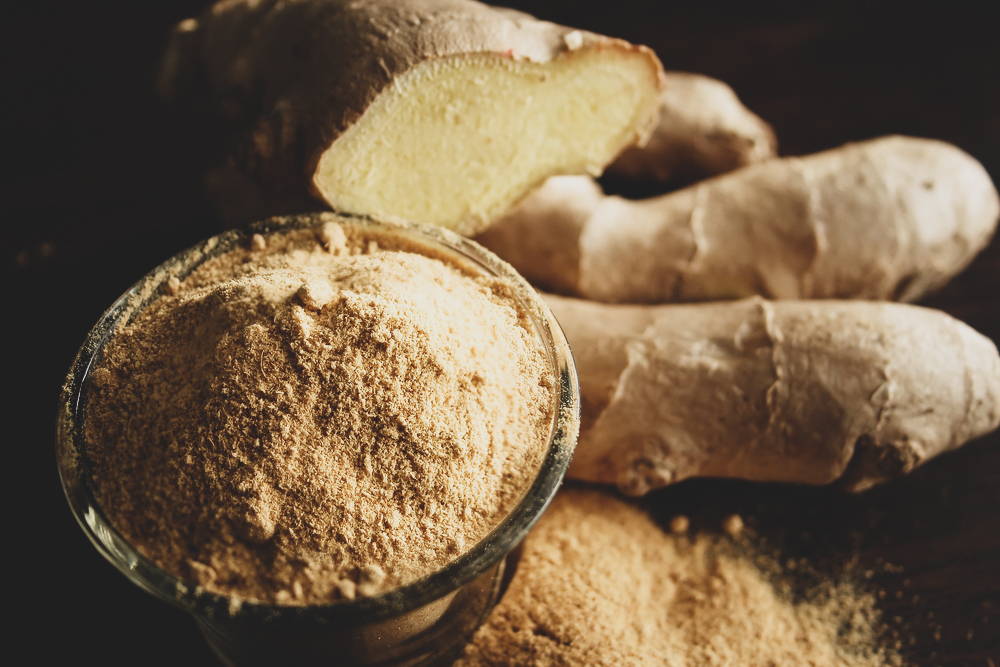 Ginger roots and powder in bowl