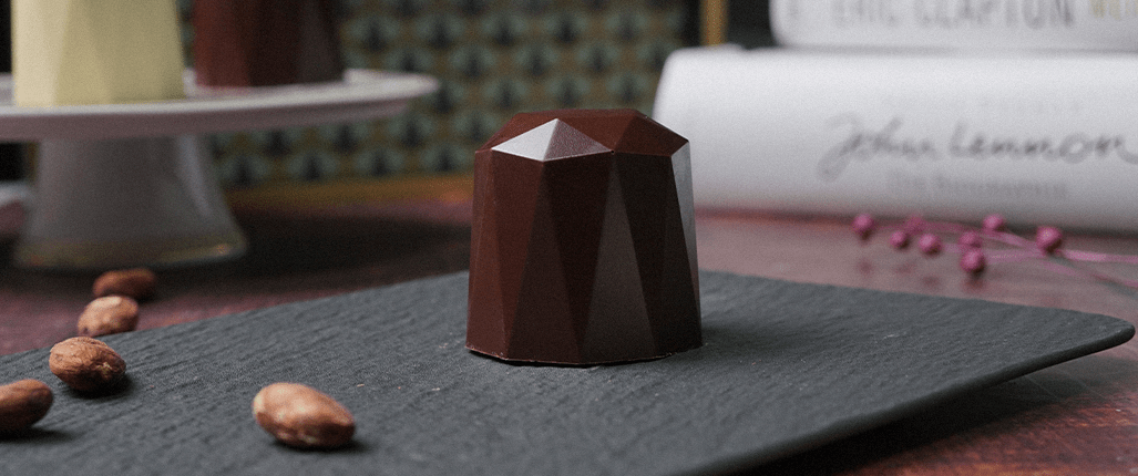 Formschöner Schokokuss auf einem Tablett mit Büchern im Hintergrund