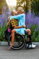 Young man in wheelchair with woman sitting on his lap and kissing him