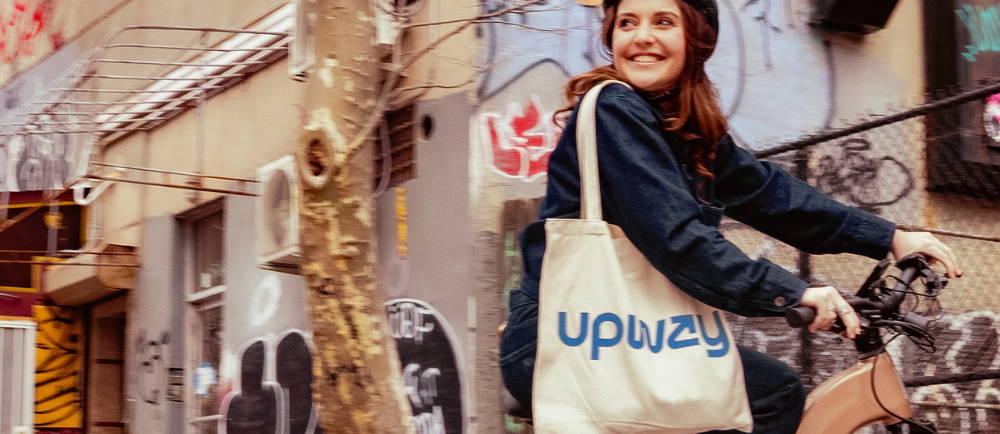 Female riding an ebike through Chinatown with an Upway bag on her shoulder