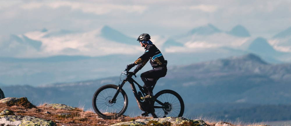 a person riding an electric mountain bike with a giant mountain behind them