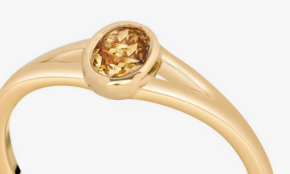bezel setting on a solitaire ring wih oval yellow diamond