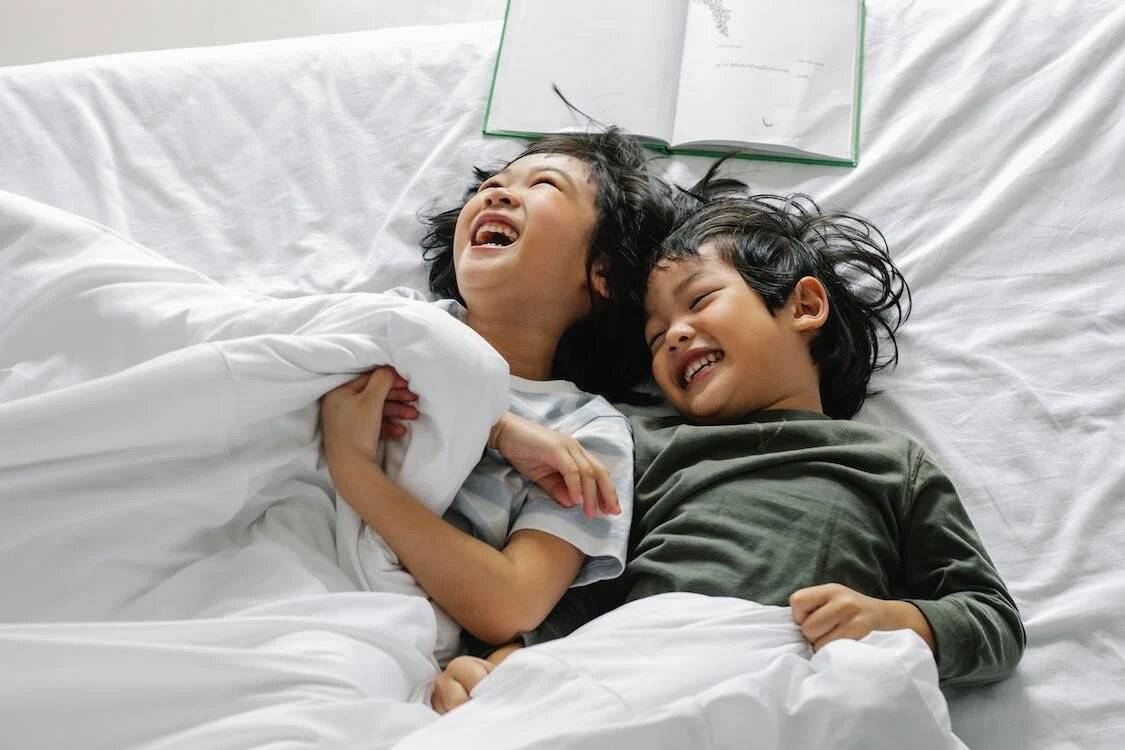 Kids laughing while lying on bed with weighted blankets
