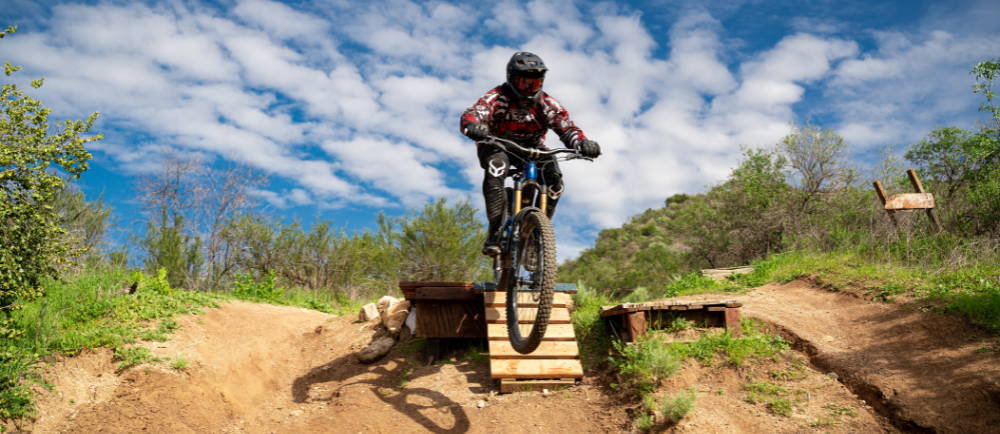 a man launching off a jump on a full suspension electric mountain bike