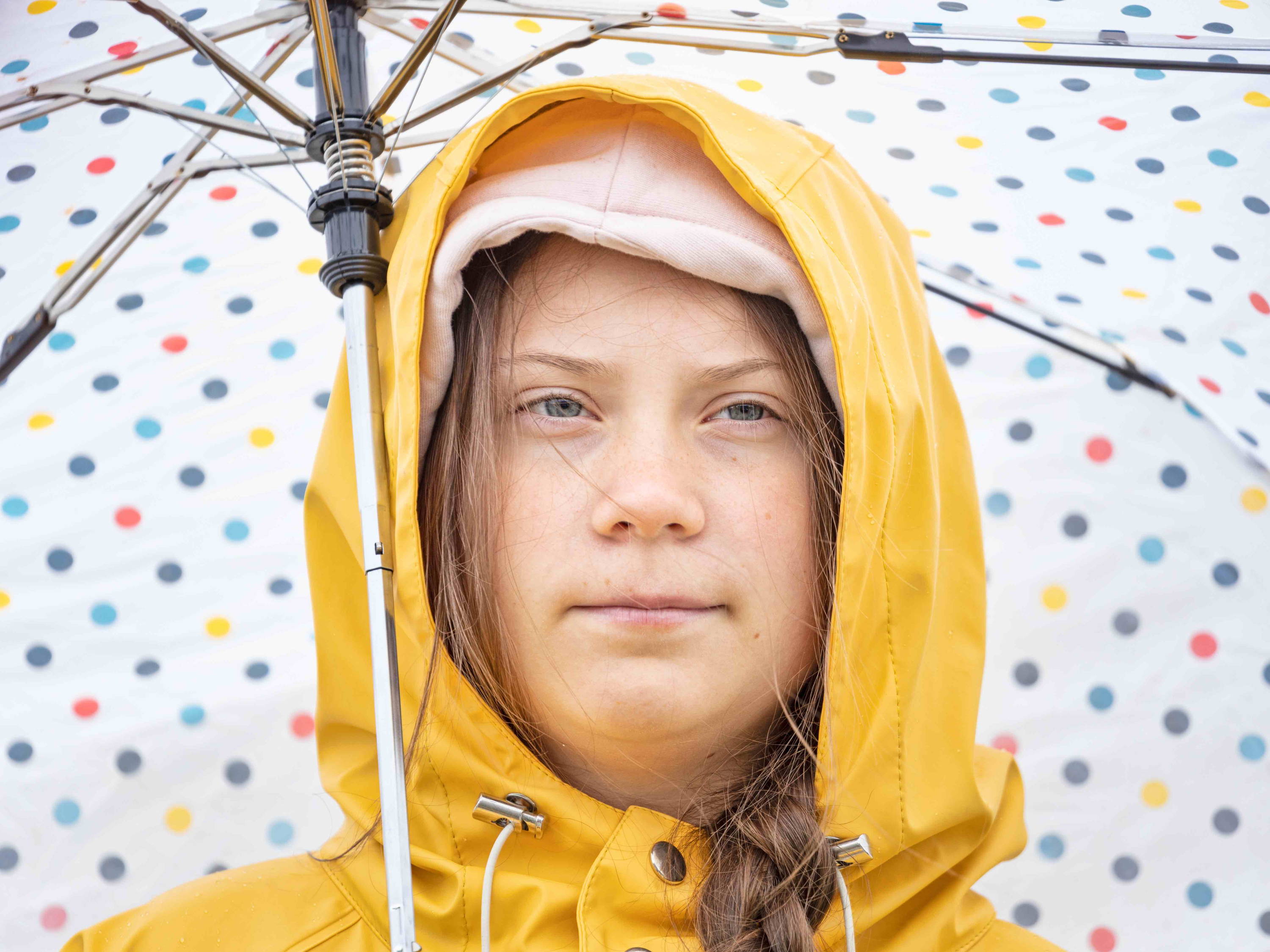 Greta Thunberg in yellow mac holding umbrella Greta Thunberg in a yellow mac holding umbrella