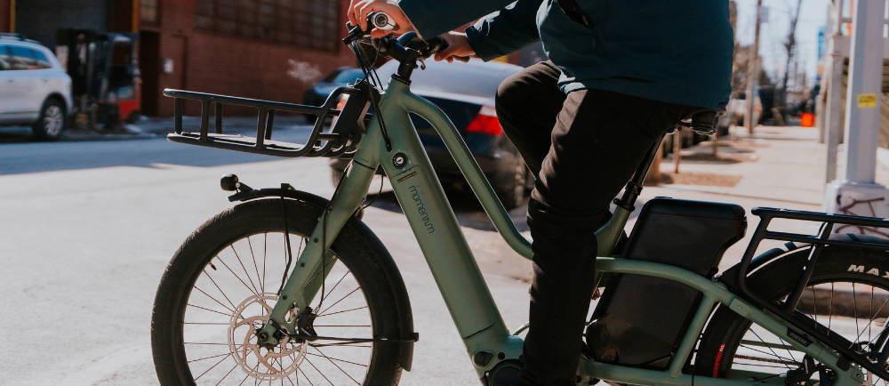 a man riding a green Momentum PakYak E+ in a city