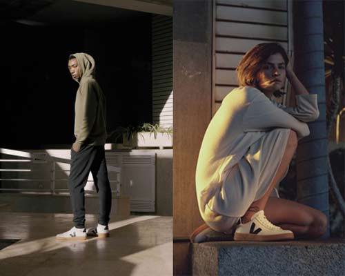 Man wearing Veja sustainable trainers in white with a natural rubber gum sole and wearing a green hoodie and black sweatpants and woman wearing the same sneakers with a white knit