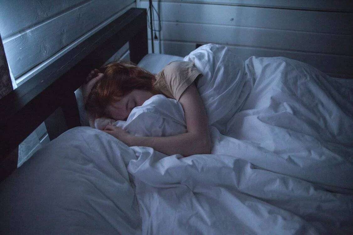 Woman dreaming at night while sleeping in comfortable sheets