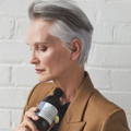 Davines model with short salt and pepper hair, holding Alchemic Silver Shampoo