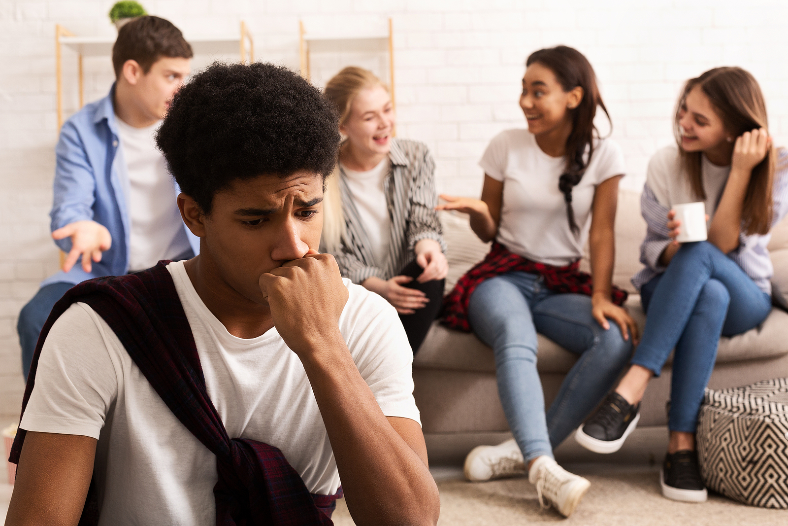 A guy looks worried while a couple friends behind him talk comfortably.