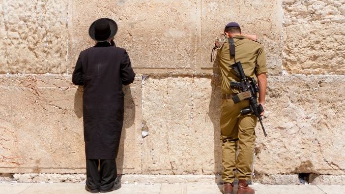 Soldier and orthodox jewish man pray at the western wall, Jerusalem