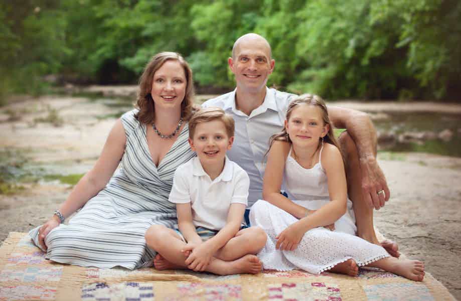 Tim and Julie Henry along with their two children sitting on a blanket by a river