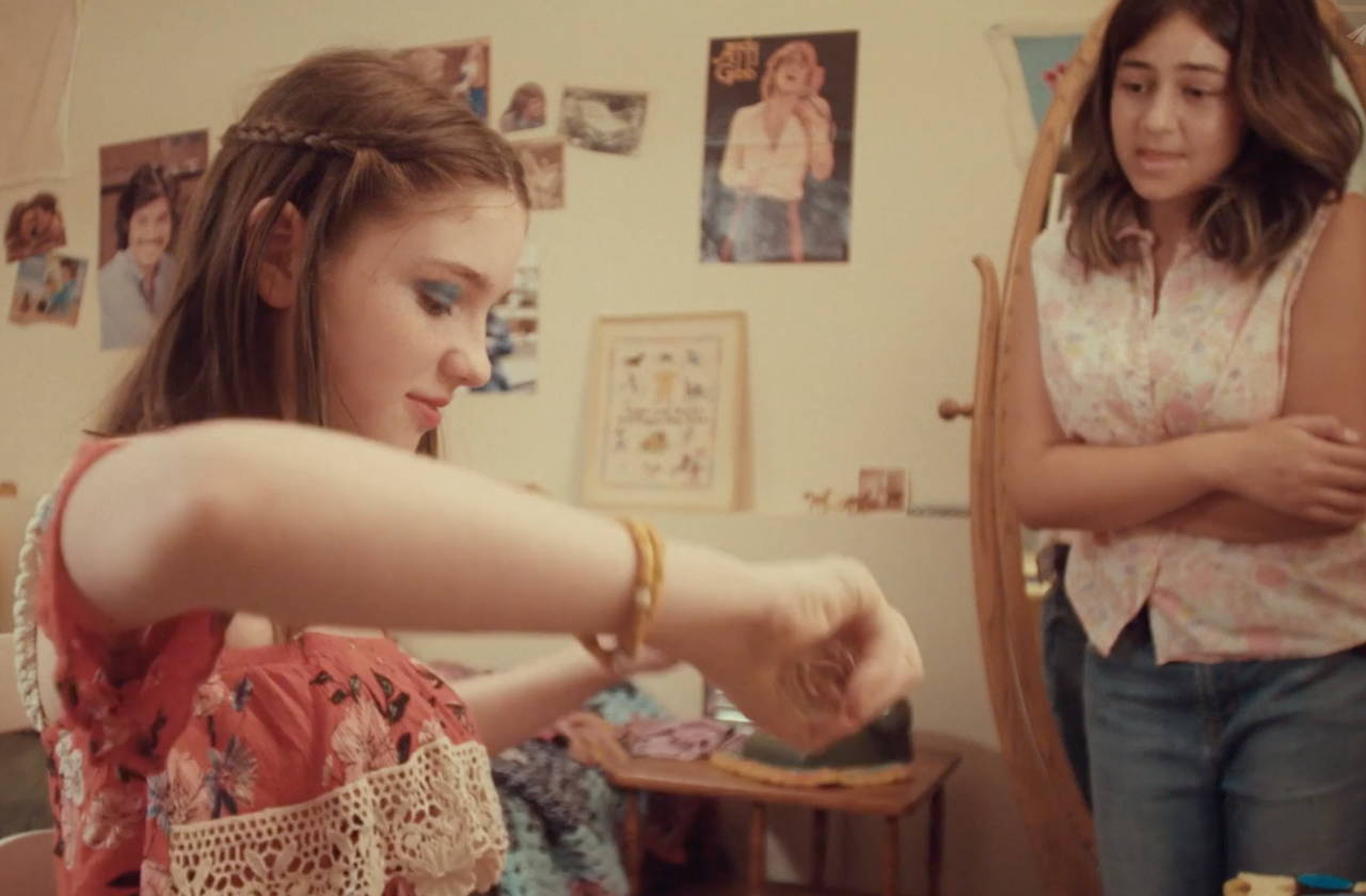 Two teenage girls; one spraying on her Love's Baby Soft cologne.