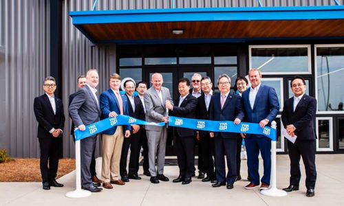A group at a ribbon-cutting ceremony in front of a modern building, symbolizing celebration and new beginnings.