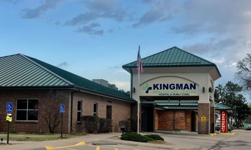 Brick building with a green metal roof, flag, and organized parking, evoking calmness, community, and reliability.