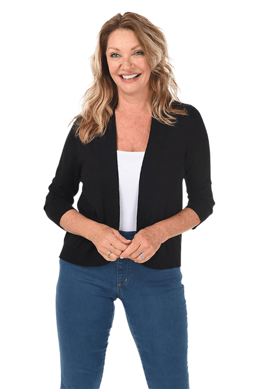 A woman wears a black cardigan over a white top and blue jeans