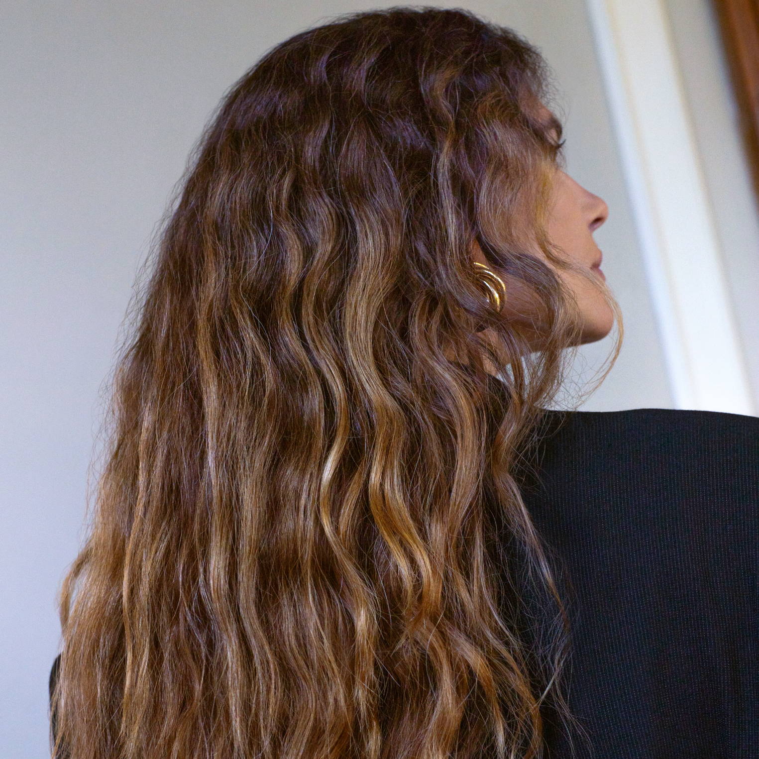 Back of woman's long wavy hair that is a blend of dark and medium brunette shades
