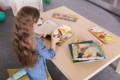 Preschooler girl reading coloruful ilustrated books.