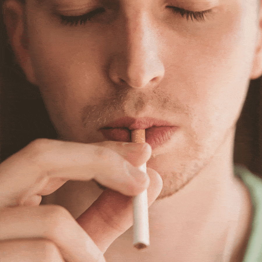 Close-up of a hand bringing a cigarette to the mouth
