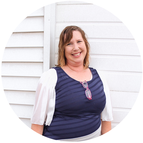 Portrait of Tami Thompson smiling in a professional outfit, standing in front of a white background.