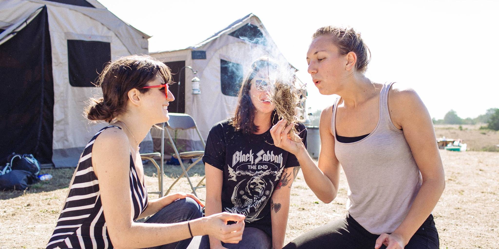 Three women starting a fire outside of their tent