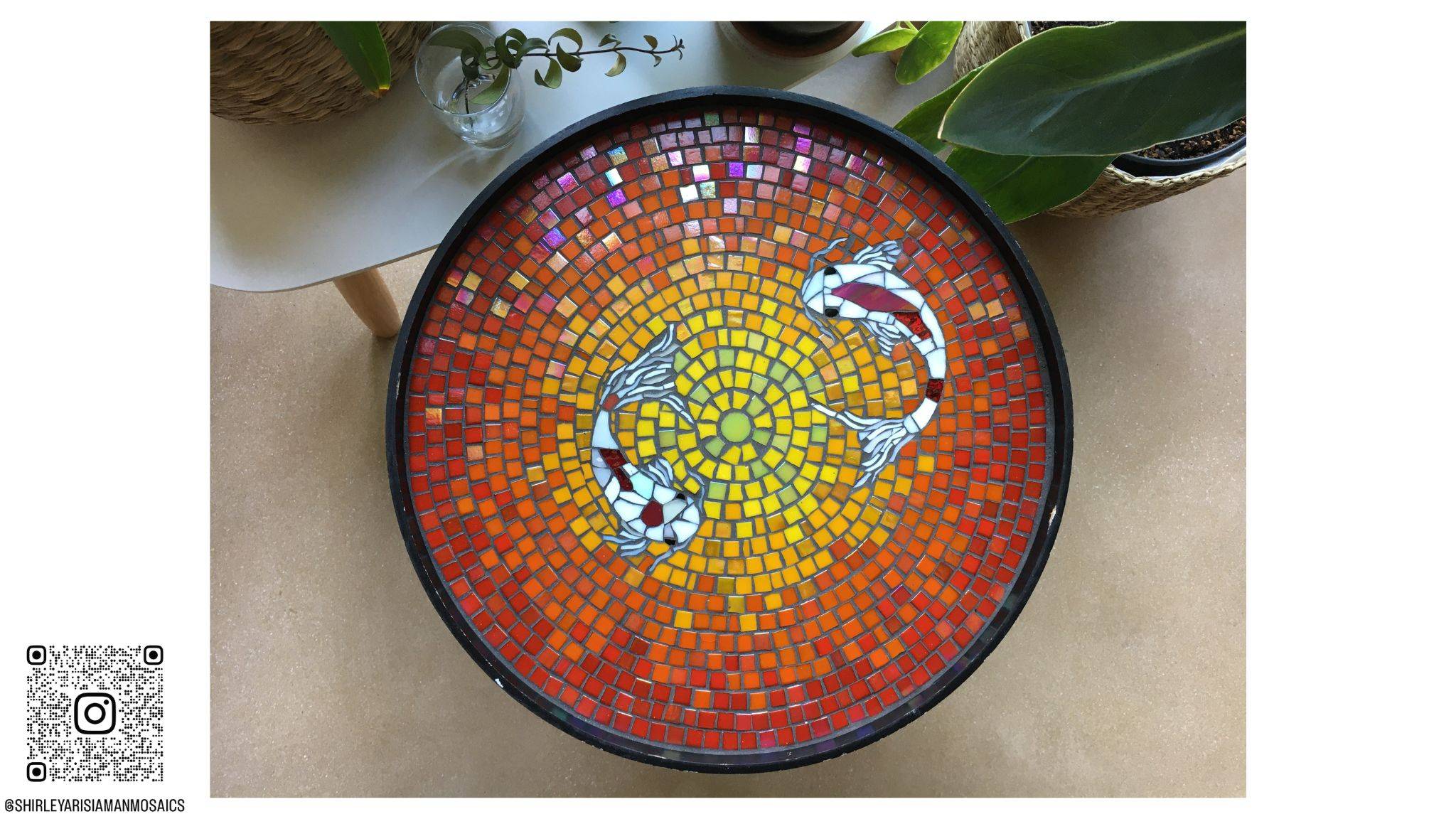 Rond tafelblad in mozaiek met 2 koi vissen op een rode achtergrond die naar geel verloopt. Gemaakt in glasmozaiek en iriserende glasmozaiek. De vissen zijn sierlijk gemaakt met Glasscherven.