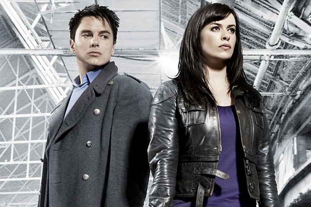 Promo image of Captain standing next to Gwen in a large building.