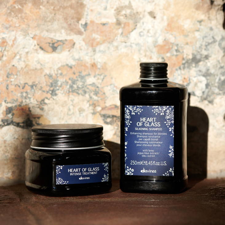 Davines Intense Treatment and Silkening Shampoo sitting on a brown table in front of a brick wall