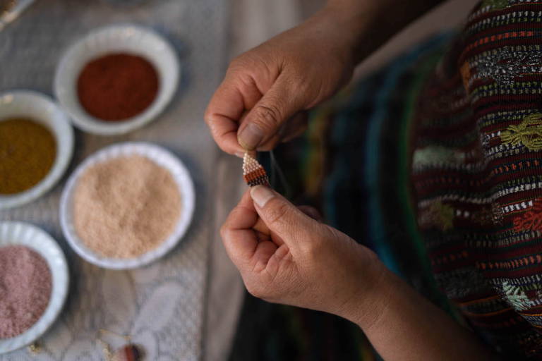 Artisan weaves a beaded earring.