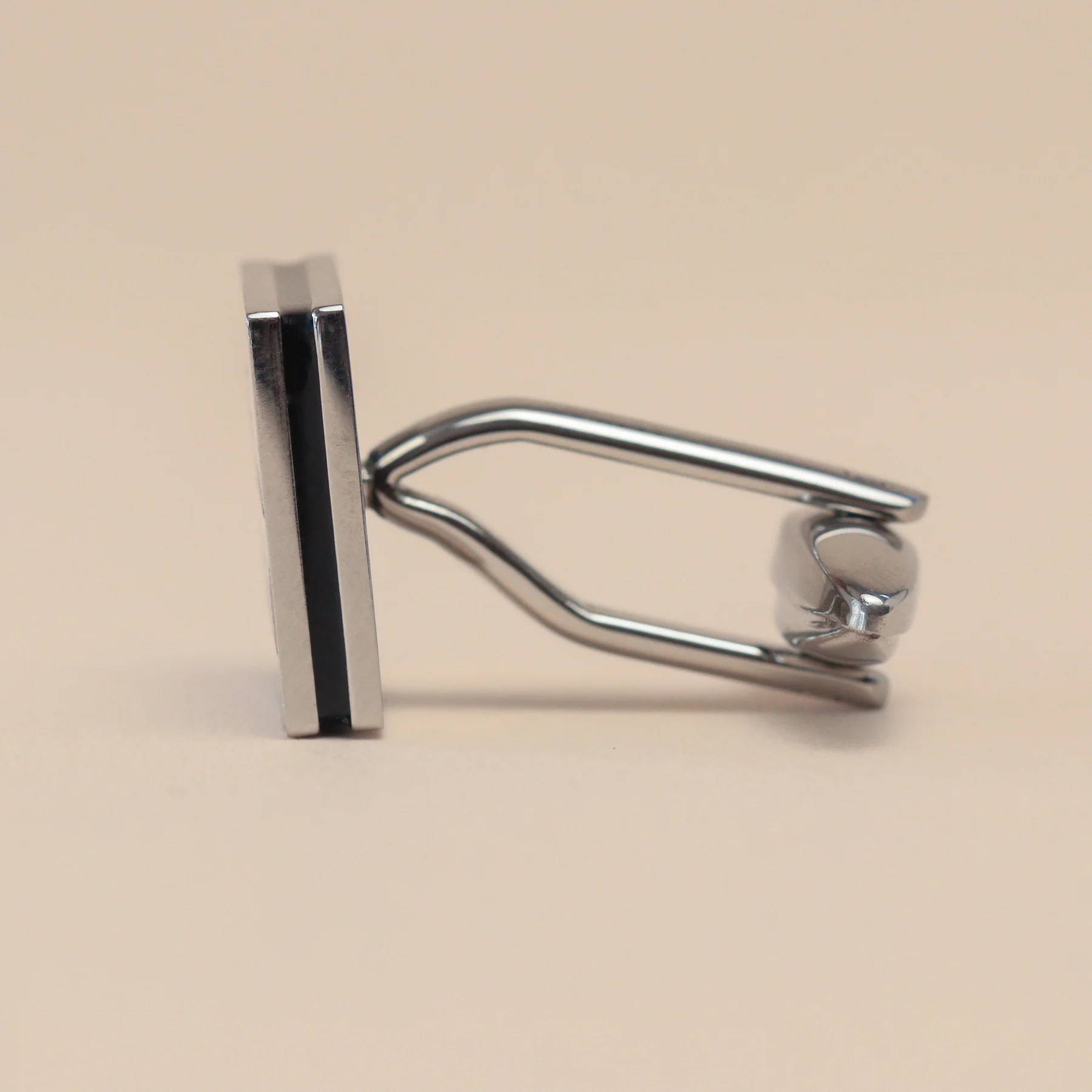 Close up image of a pair of polished stainless steel cufflinks with a bottle of Henderson's Relish engraved on the face.