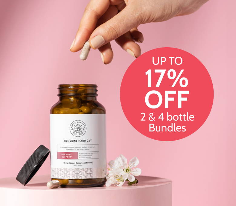 Hand holding capsule above Hormone Harmony bottle with pink discount label and flowers.