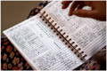 a woman with an open everyday mother book in her lap, showing how she has used the journal to track her baby over two days