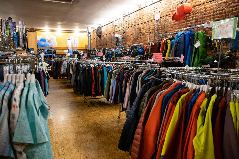 Many clothing racks full of used men's and women's apparel.