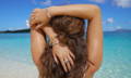 A woman wears ocean inspired jewelry next to the ocean.