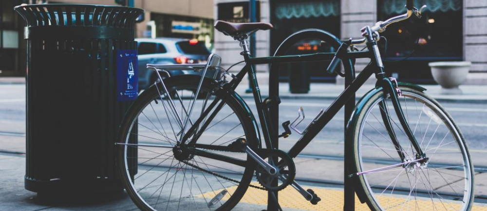 Single speed bike locked to bike rack near street