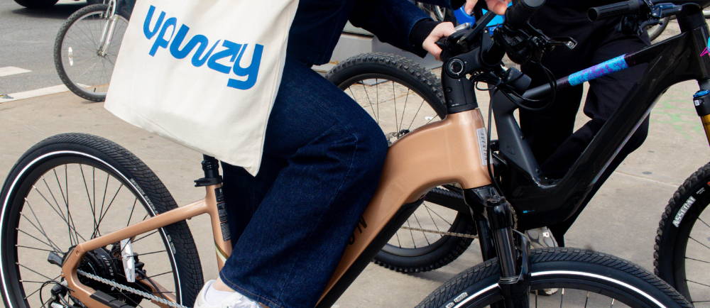 two people riding electric bikes in chinatown and a woman carrying an upway handbag