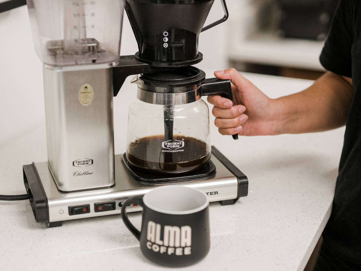 Hand grabbing coffee pot on a Mocca Master.