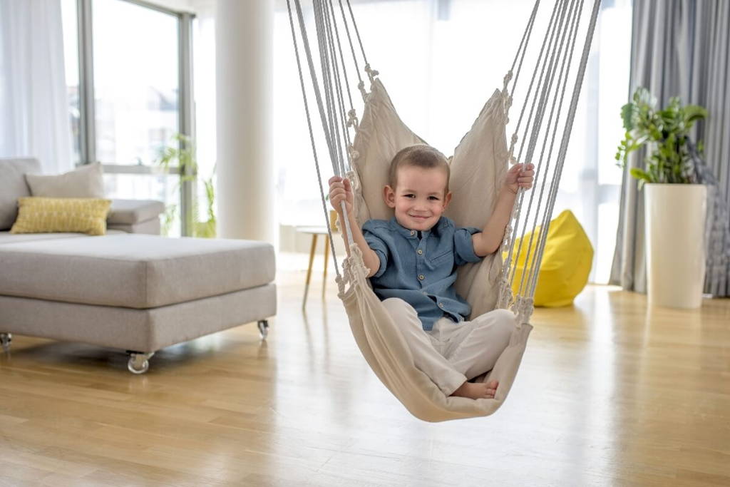Little boy enjoy sitting in a swinging sensory hammock.