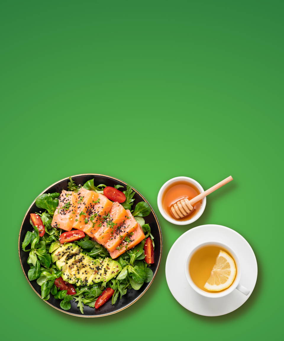 A salad with avocado and salmon next to a cup of green tea and a bowl of honey for Confetti's Virtual Eating for Immunity