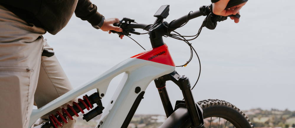 a man gripping the handlebars on a full suspension cannondale electric mountain bike