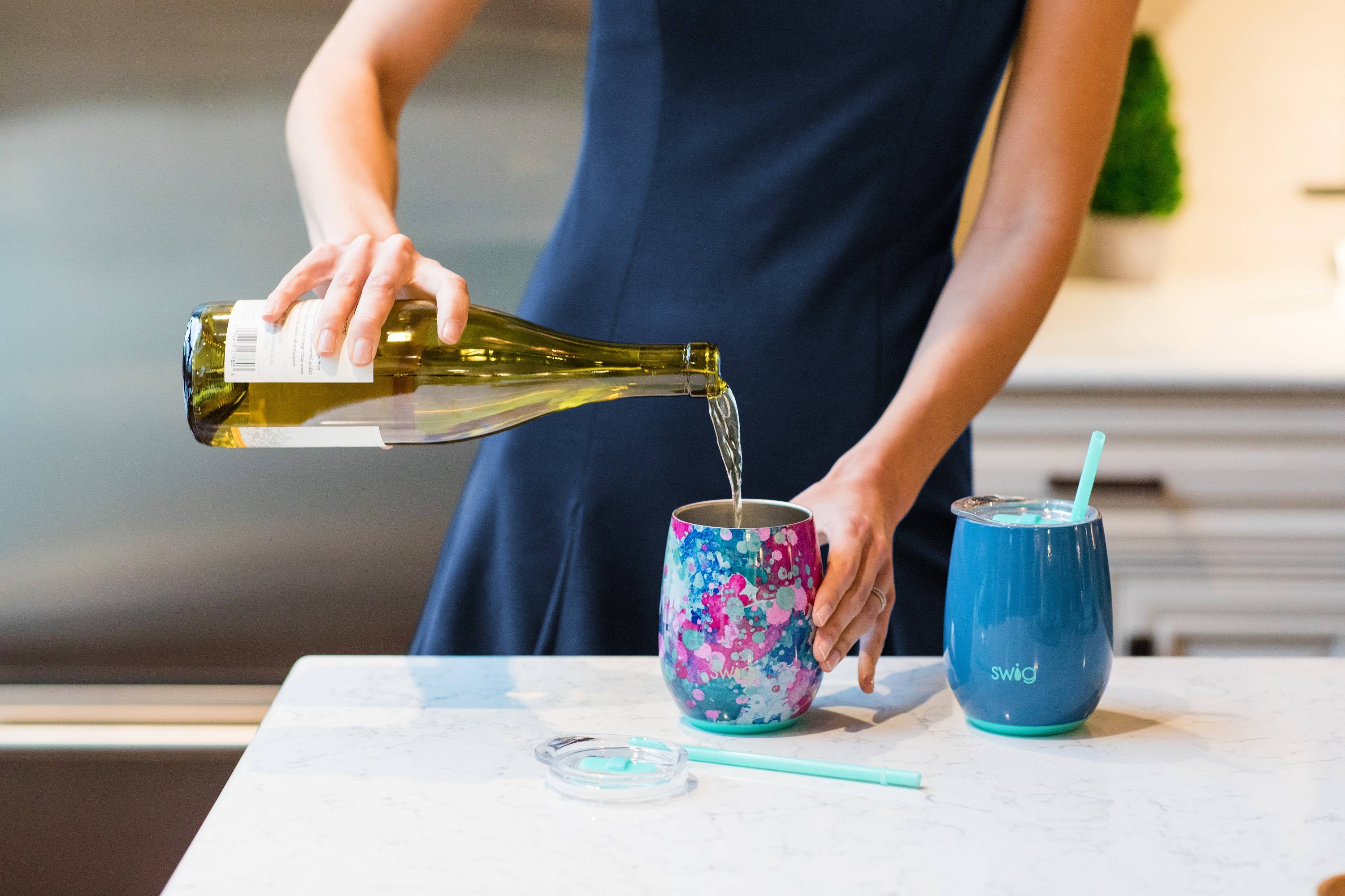 A woman pours wine into a Swig wine cup
