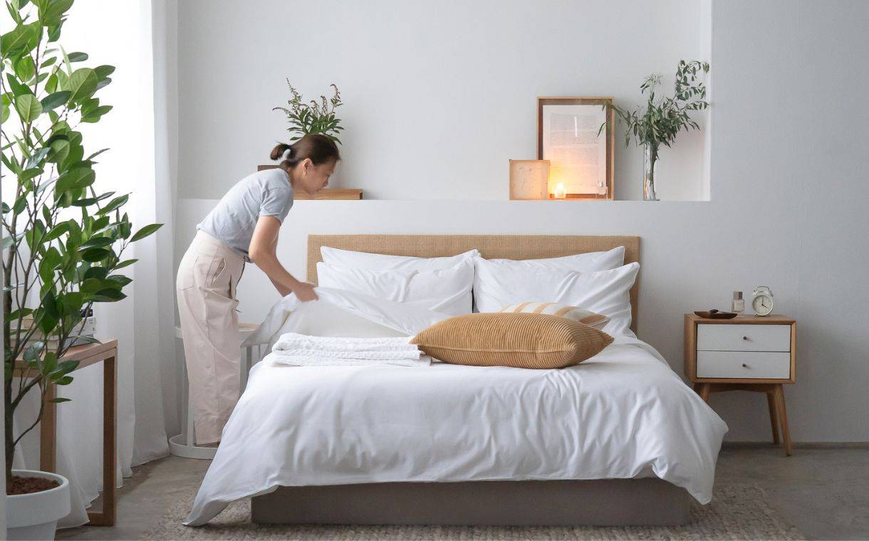 Woman making bed with Weavve's white cotton bed sheets